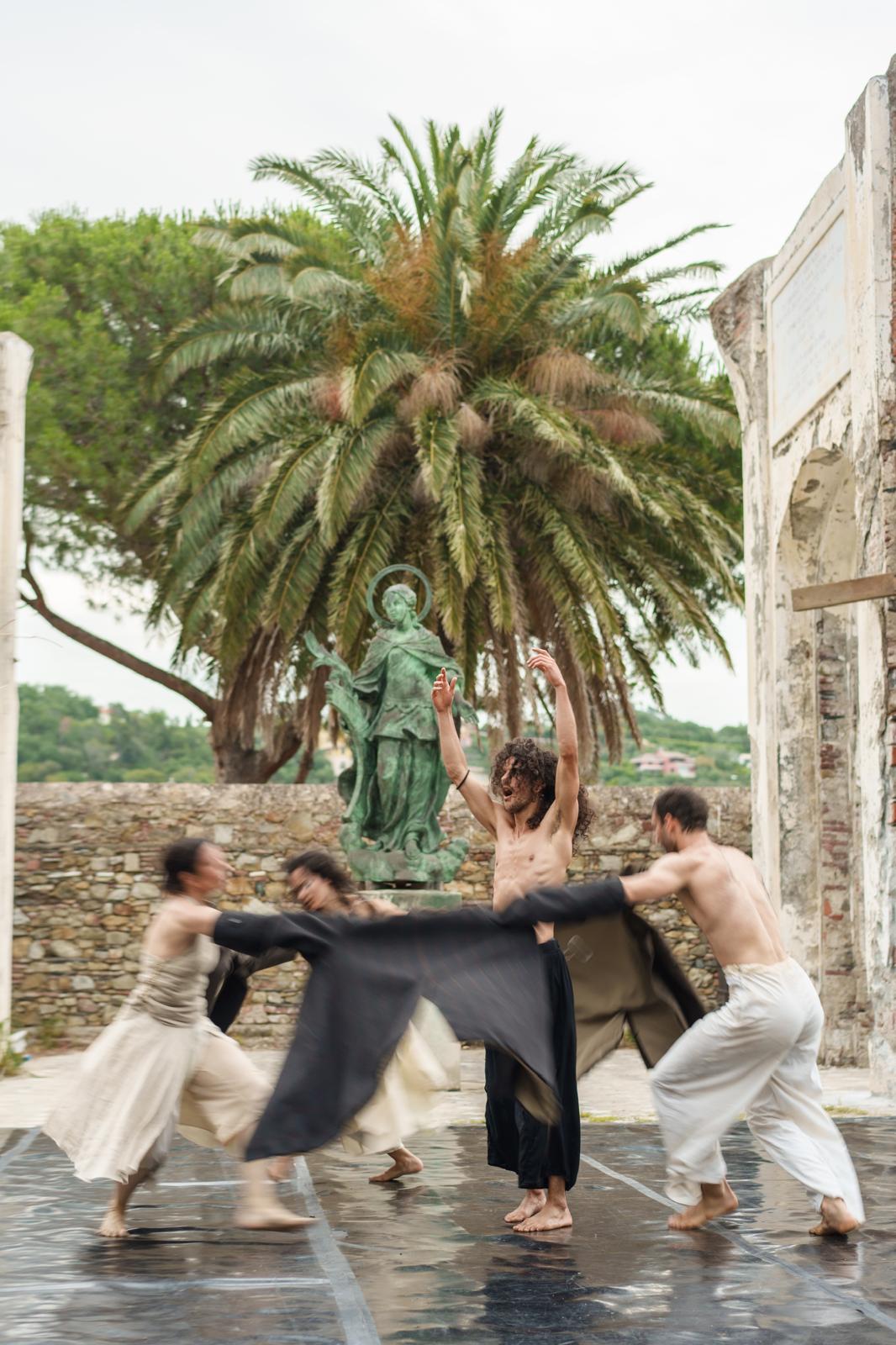 A dancer raises his arms as other dancers move around him.