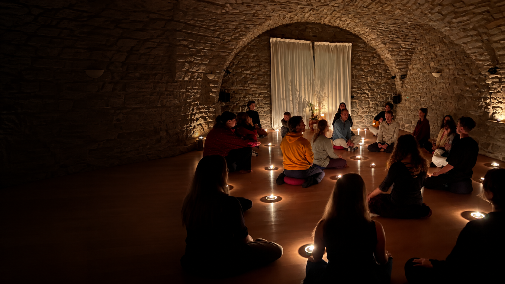 Il gruppo del retreat siede in un cerchio di candele nella sala in pietra con volta del Convento.