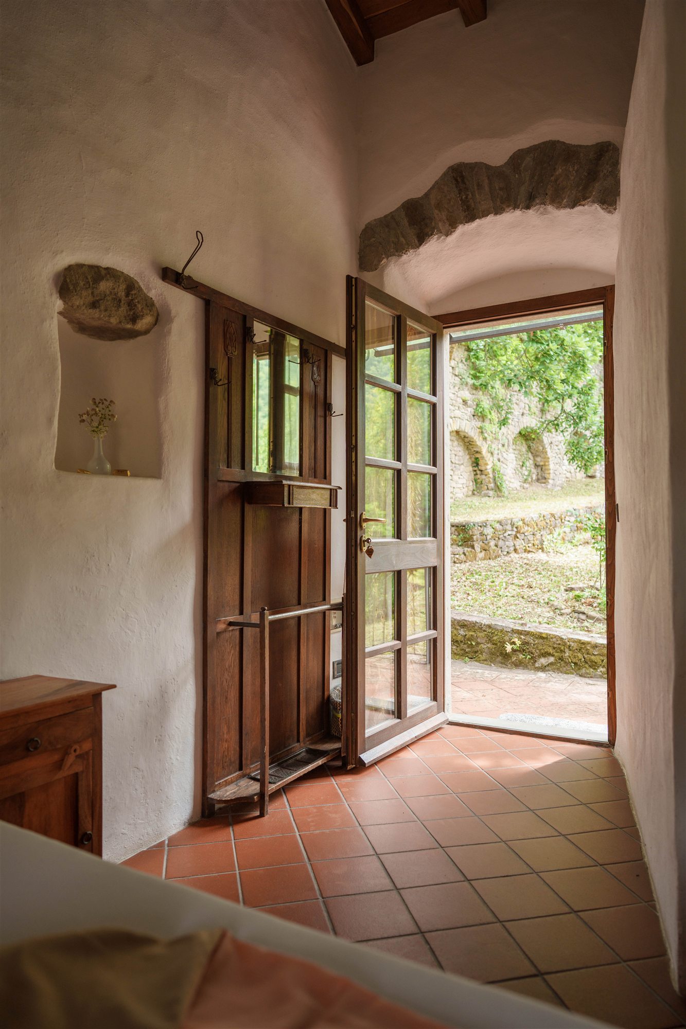 An open wooden door leads directly from the room into the garden.