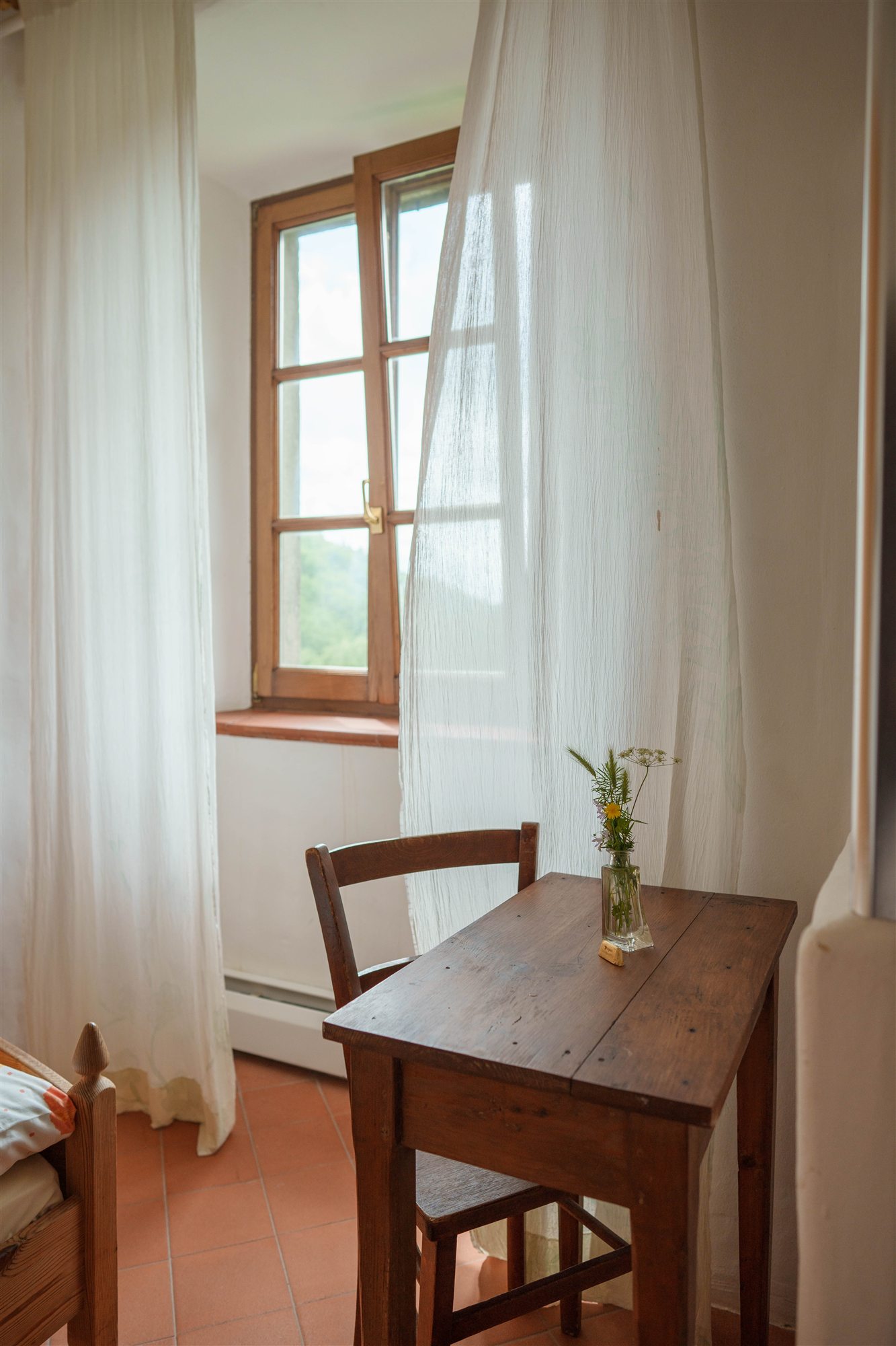 A simple room with flowers and a view towards the window.