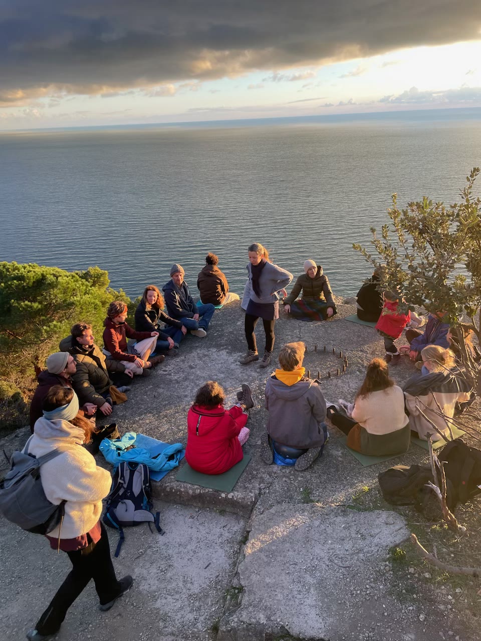 The retreat group sits in a circle above the sea in the evening light.